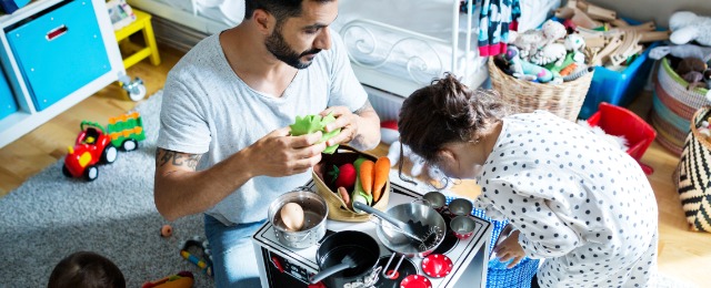 father and child playing with toy kitchen