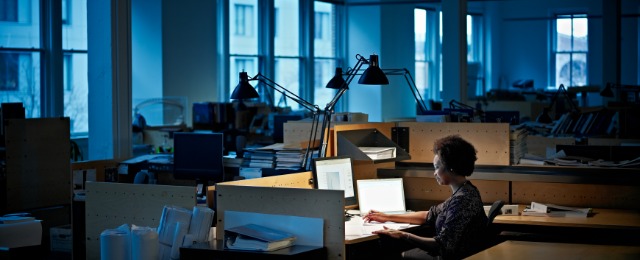 Businesswoman examining documents at desk at night