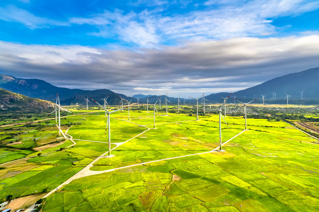 Panoramic view of wind farm or wind park. Green meadow with Wind turbines generating electricity